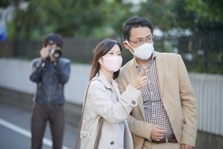 岐阜浮気調査相談室の調査員が、対象者2名の行動を遠距離から正確に撮影している様子。調査員は植栽沿いの位置からカメラを構え、対象者はスマートフォンを手にしながら指差し確認を行っており、行動パターンの分析と先読みを前提とした“必然調査”の一場面を示す証拠撮影シーン。